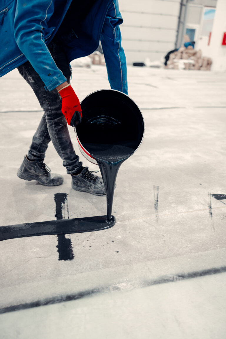 Worker applies gray epoxy reisin to a new floor