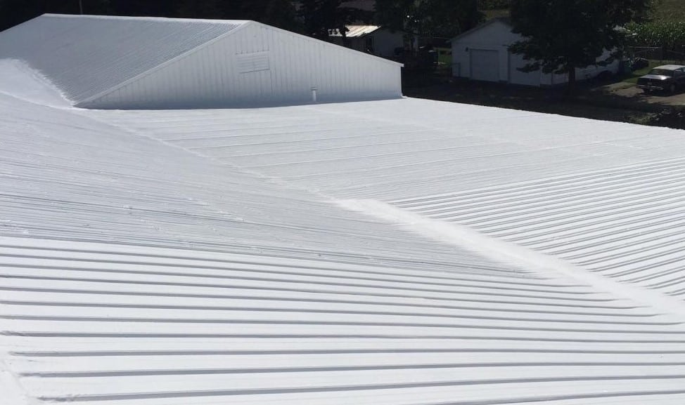 Large commercial building with a white metal roof featuring multiple slopes and roof sections.