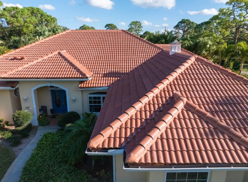 Aerial view of a Florida home with a terracotta tile roof, multiple roof sections, and tropical landscaping.