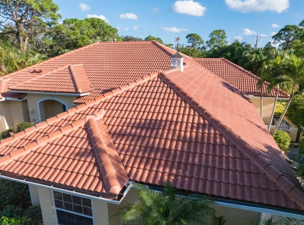 Aerial view of a Florida home with a terracotta tile roof, multiple roof sections, and tropical landscaping.