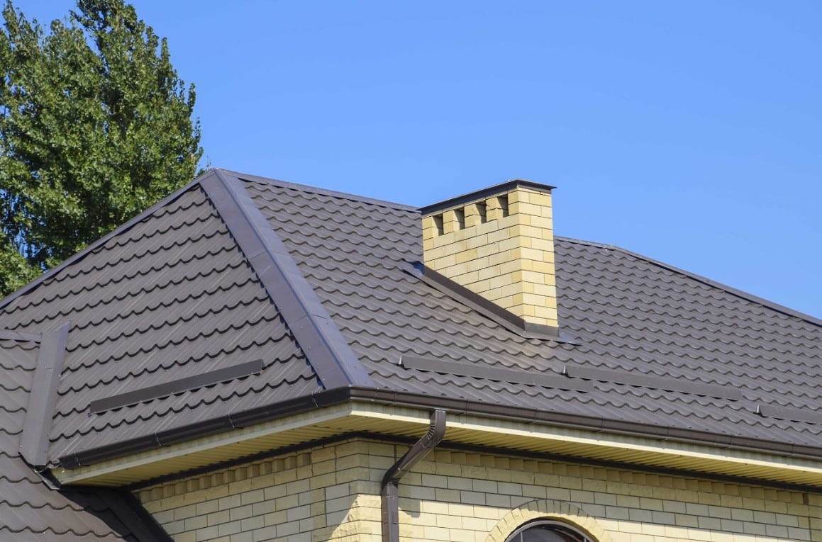 Dark metal tile roof installed on a brick home