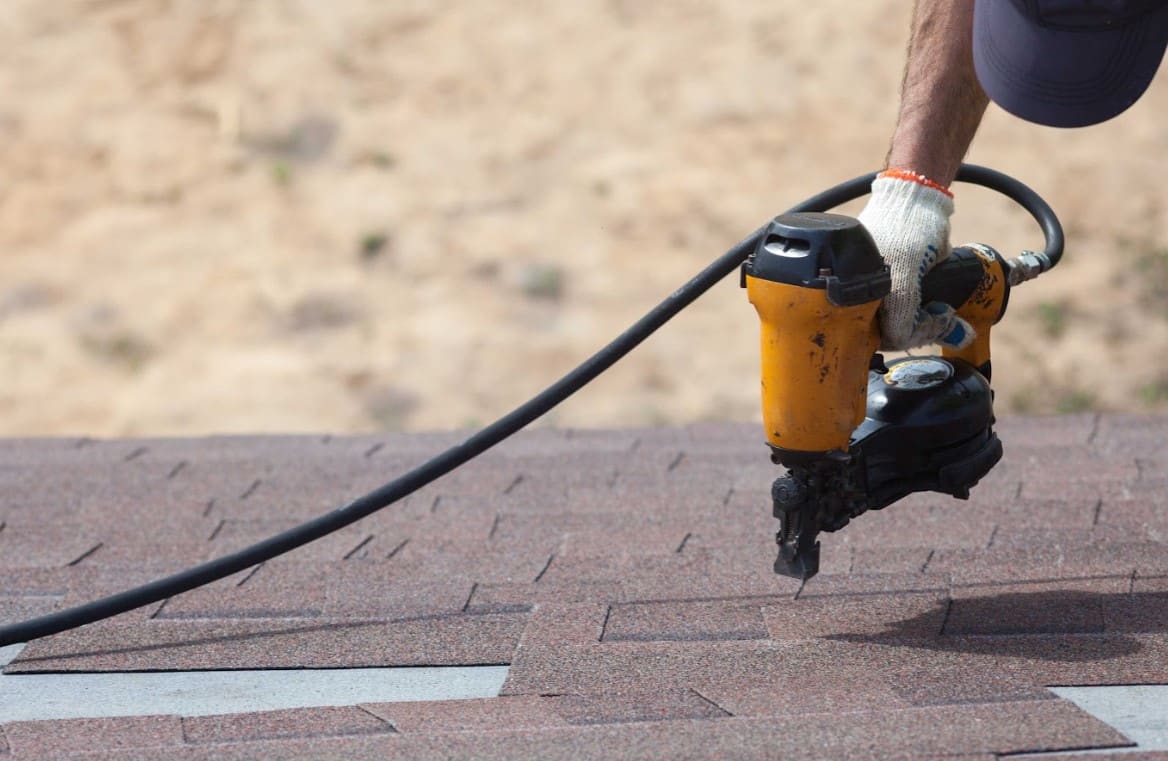 Contractor in a process of roof repair using a roofing equipment in Florida