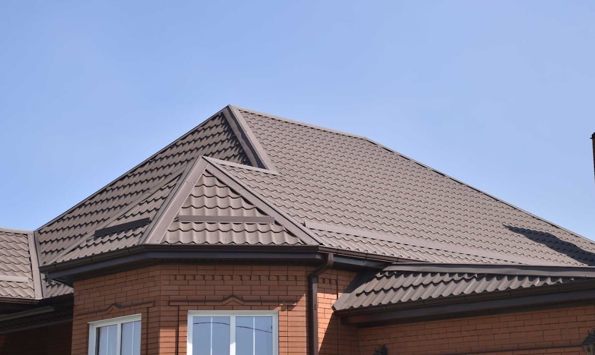 Dark metal tile roof installed on a brick home