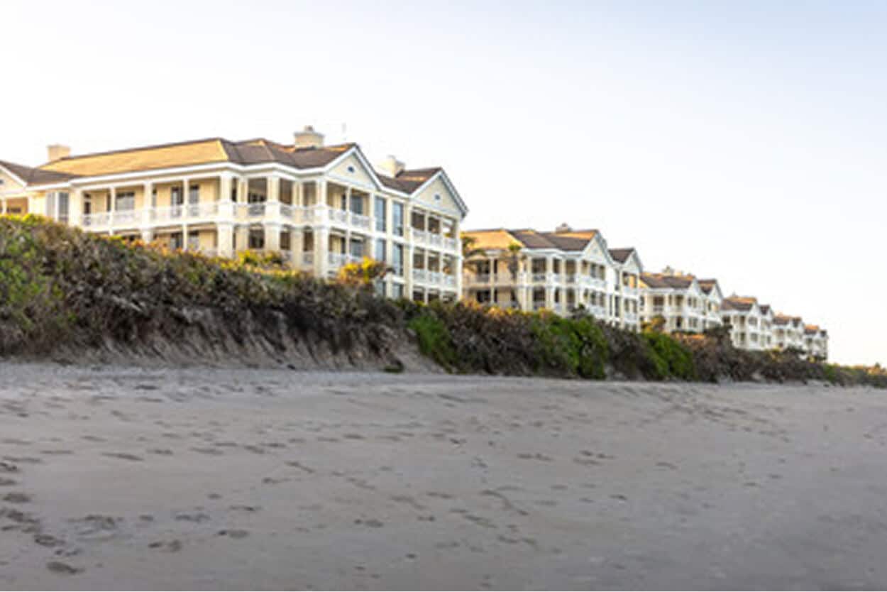 A row of multi-story, coastal yellow condominiums line the sandy beach shore of Brevard County, Florida
