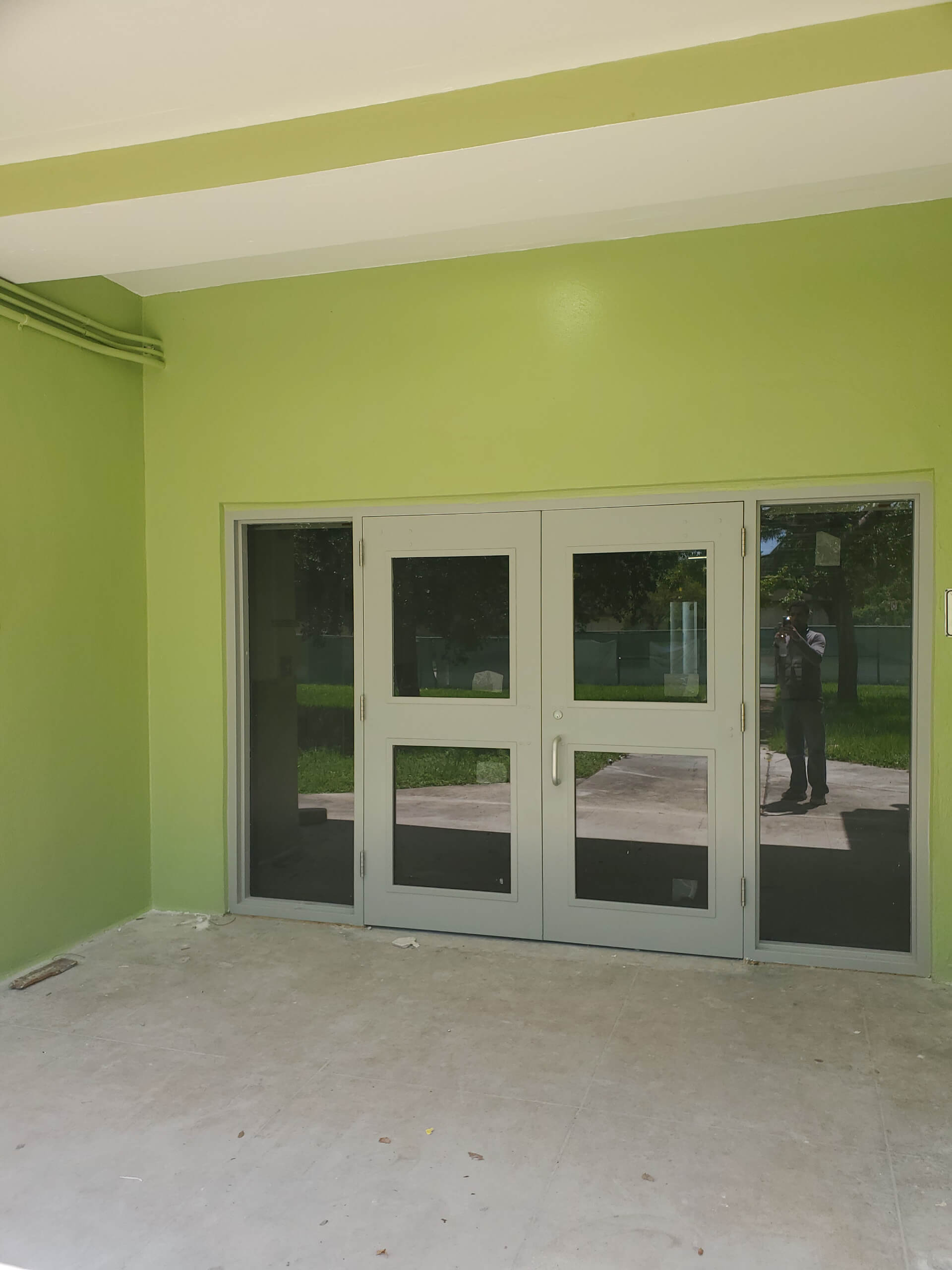 White impact double doors with glass panels and matching sidelights installed on a commercial building