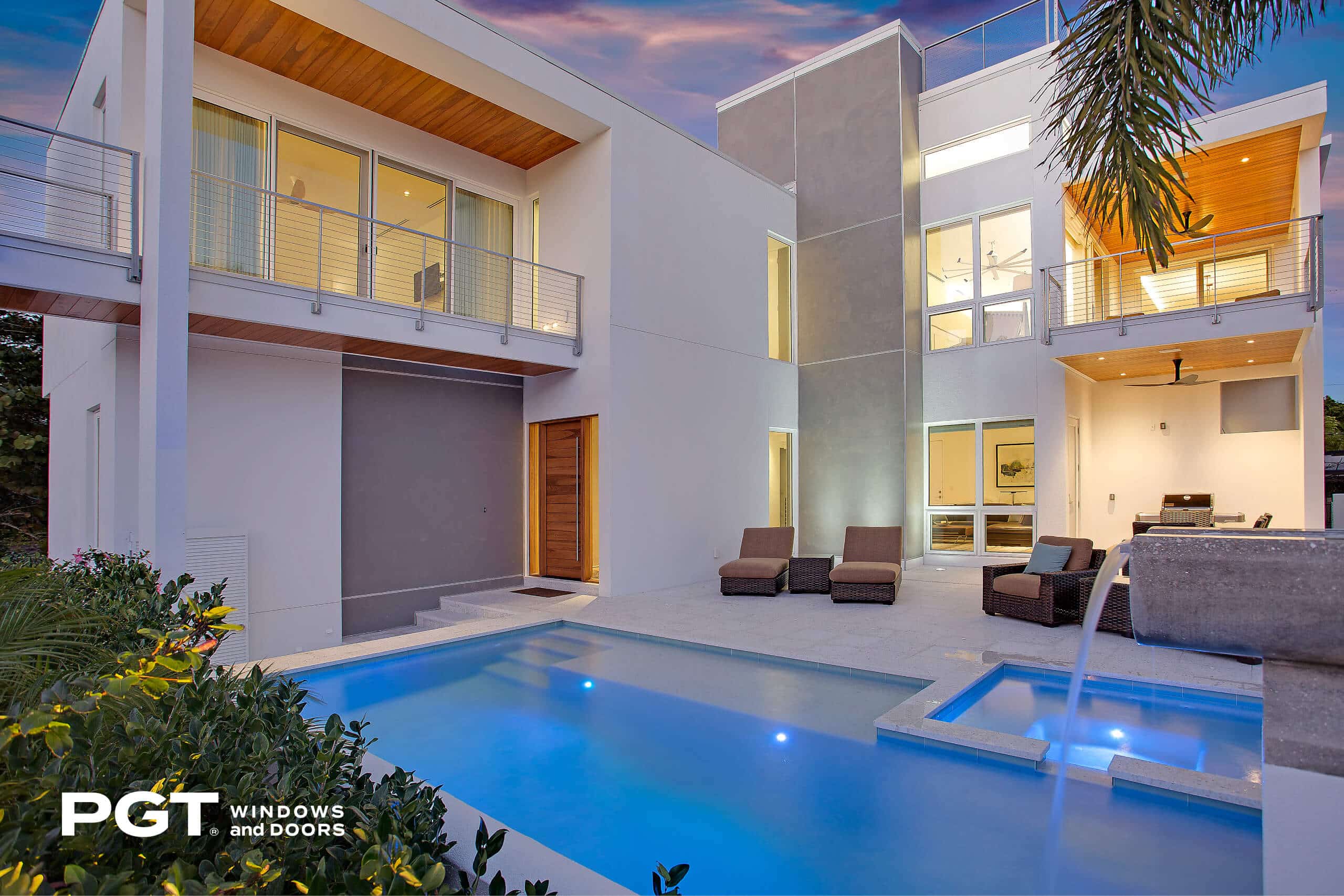PGT impact windows and sliding glass doors surrounding a modern home with a backyard pool