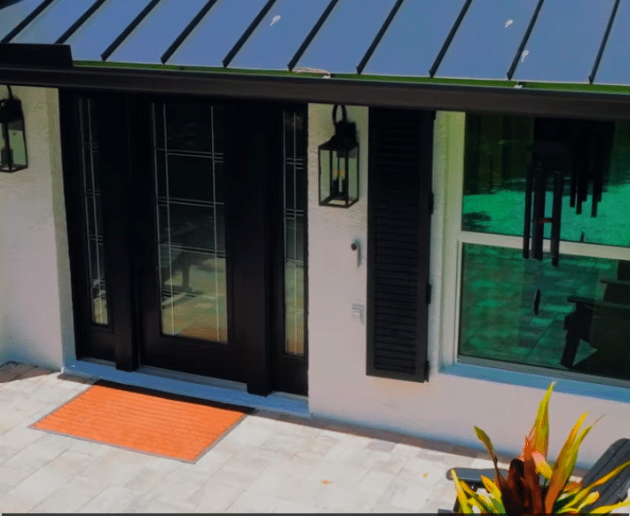 Black impact double front doors with decorative glass panels beside a matching impact window