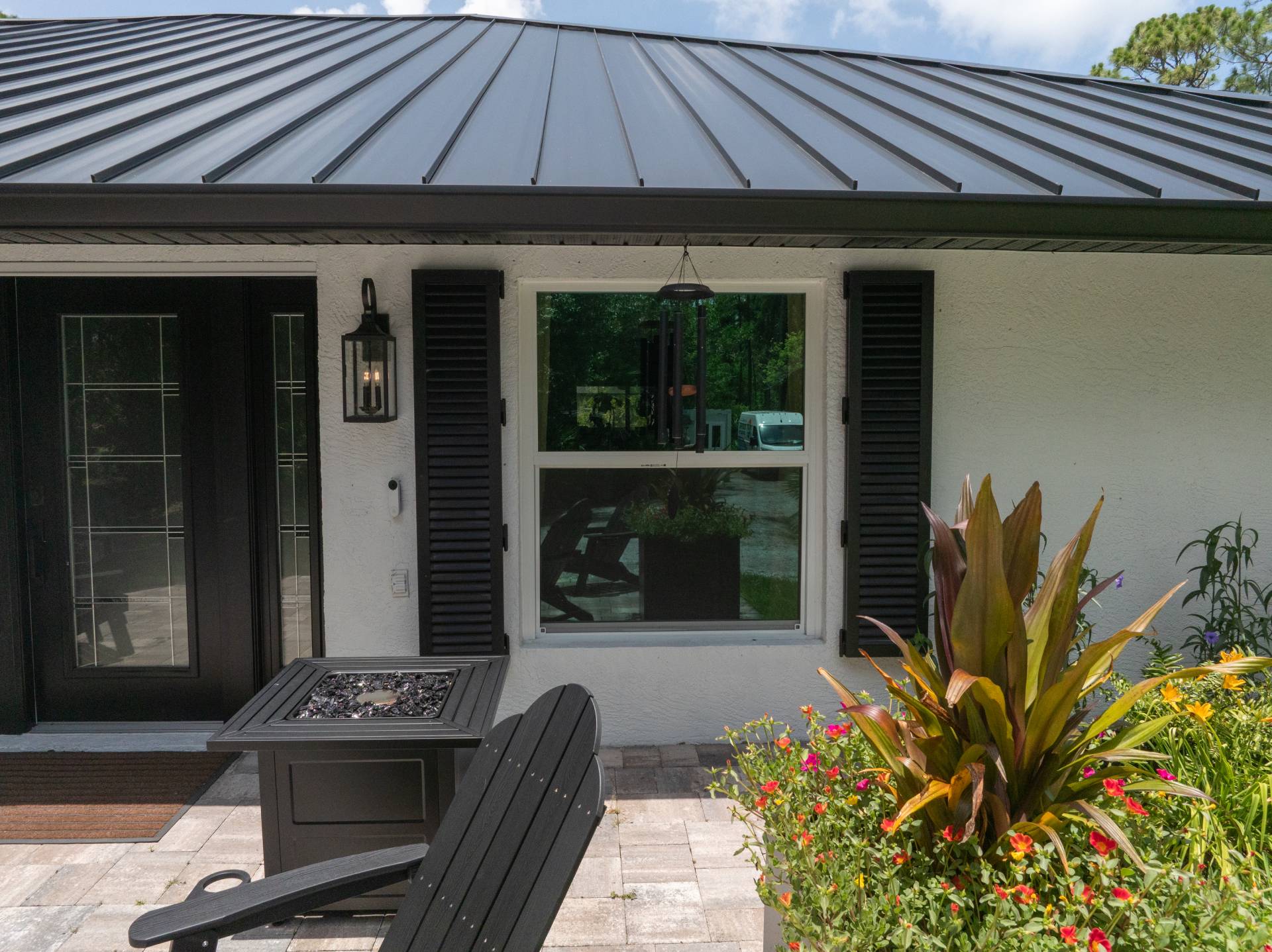 Black front door and impact window beneath a standing-seam metal roof on a Florida home