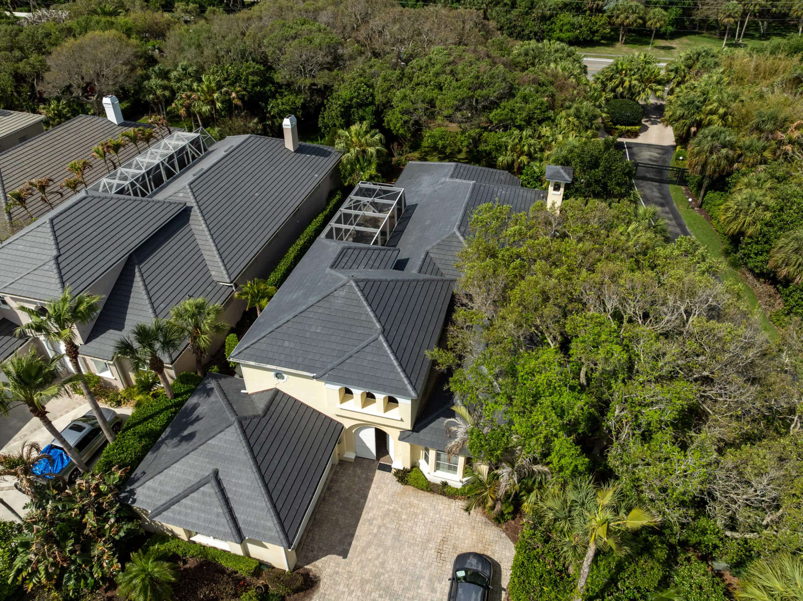 Aerial view of a completed black metal roof replacement on a Florida home with a backyard pool