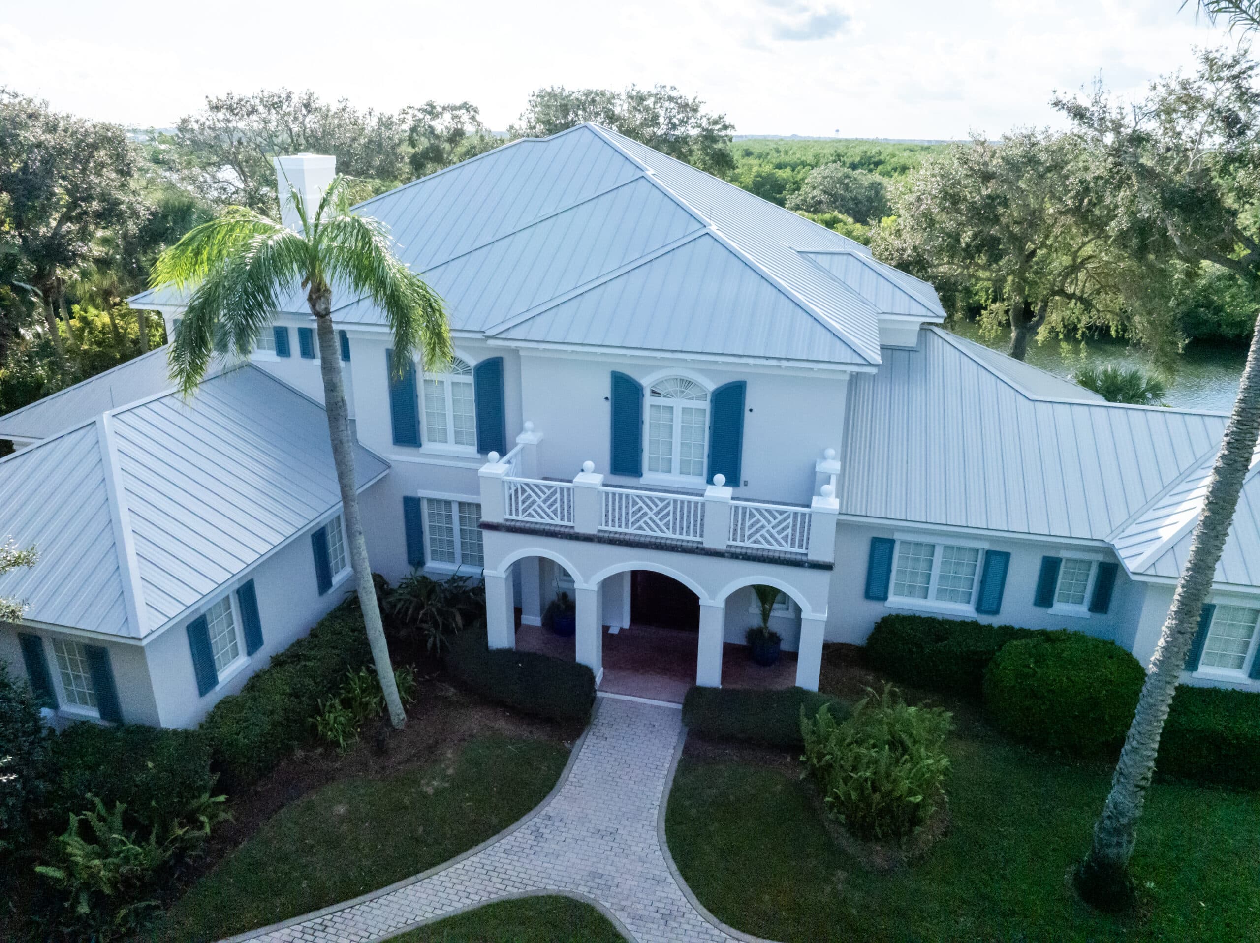 Aerial view of a completed white metal roof replacement on a large Florida home