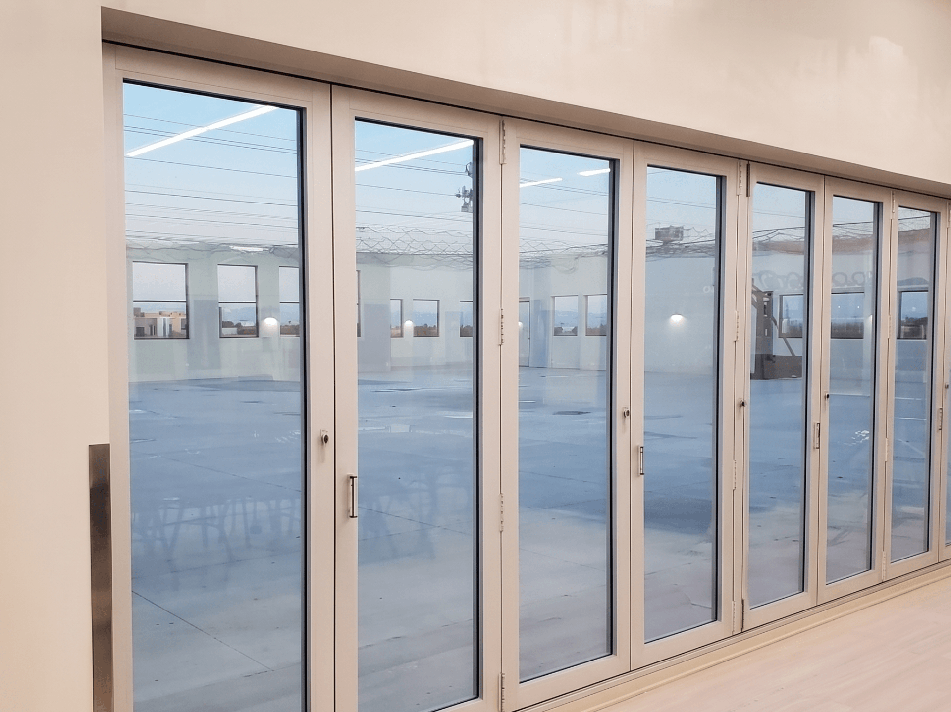 White-framed impact doors opening to an outdoor patio area