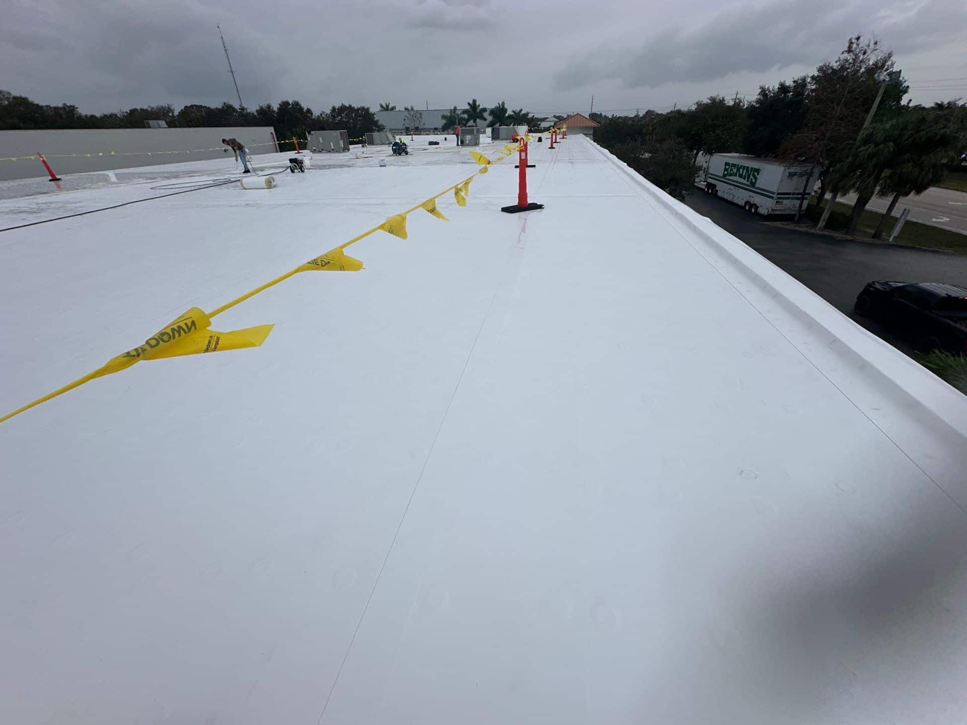 arial view of a white commercial flat roof with yellow flags across it