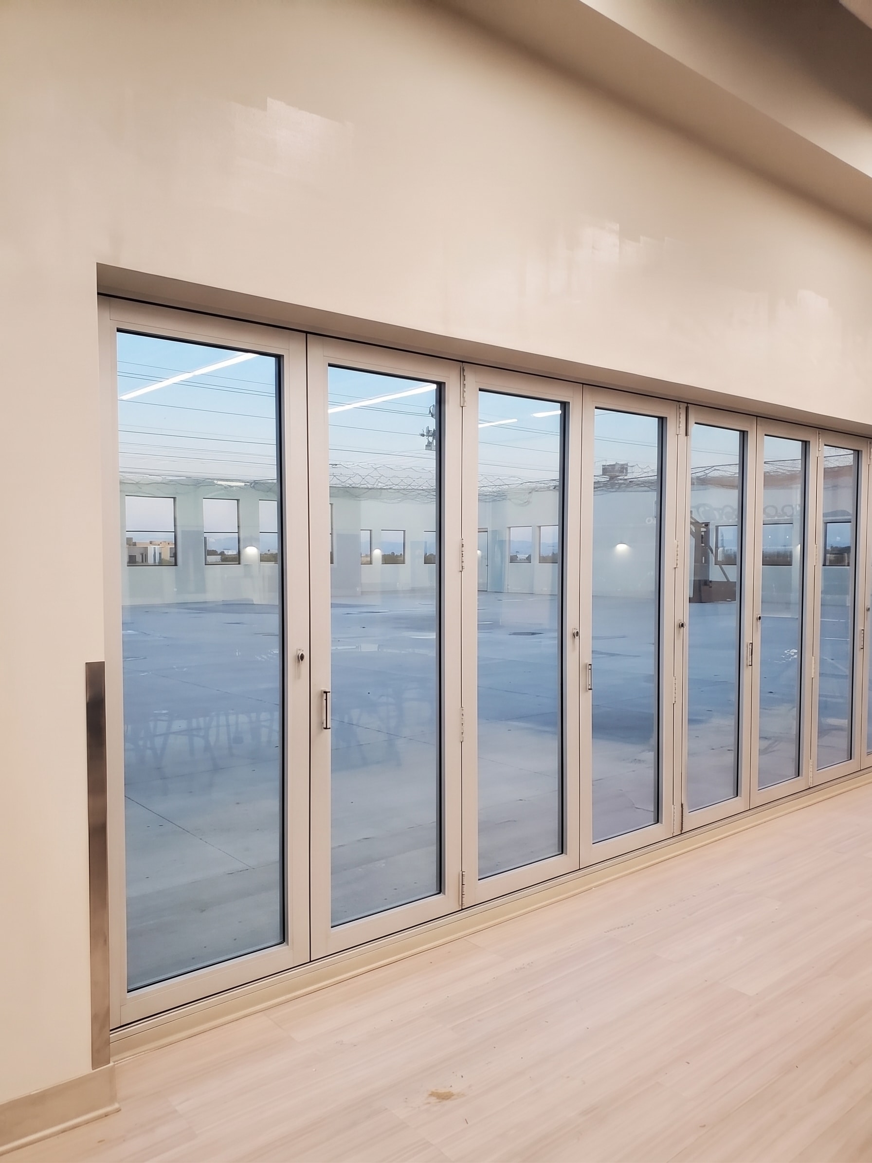 White-framed impact folding doors opening to an outdoor patio area
