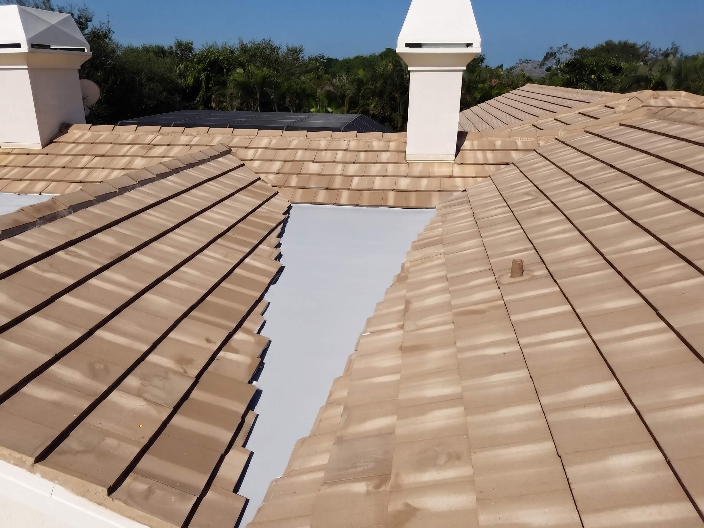 Tile roof replacement with a white flat-roof section on a Florida home