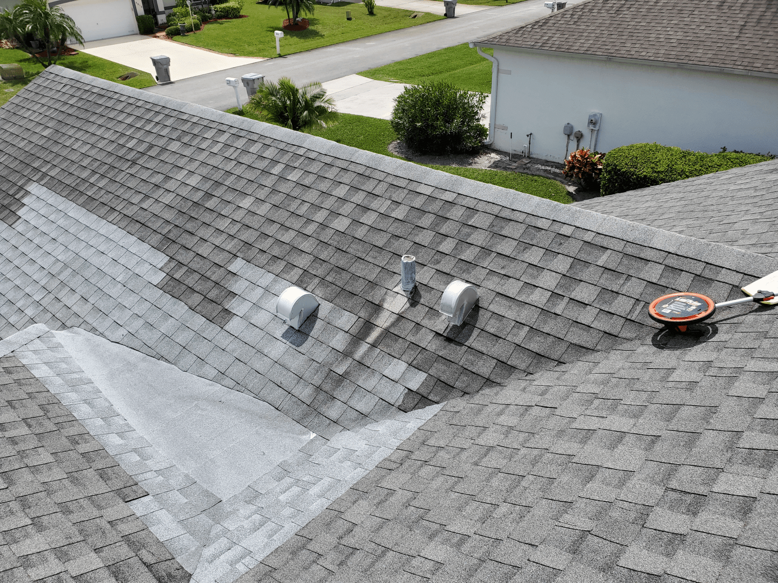 Gray asphalt shingle roof with completed repairs around the vents and roof valleys